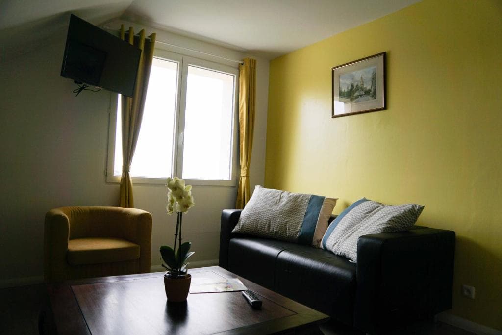 Salon avec canapé, fauteuil et télévision écran plat